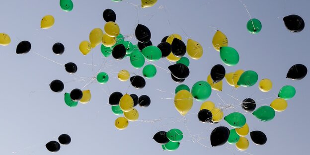 Viele Luftballons in den Farbn schwarz, grün und gelb an einem blauen Himmel Viele Luftballons in den Farbn schwarz, grün und gelb an einem blauen Himmel