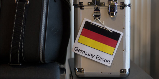 Ein Koffer trägt ein Schild mit einer Deutschlandflagge und der Aufschrift "Germany Escort"