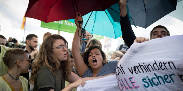 Frauen mit Regenschirmen rufen etwas Frauen mit Regenschirmen rufen etwas