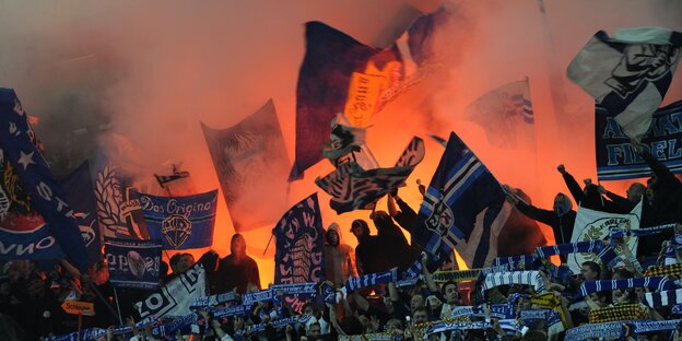 Fußballfans mit Fahnen und Feuerwerk