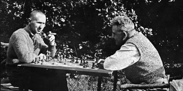 zwei Männer sitzen draußen am Tisch und spielen Schach zwei Männer sitzen draußen am Tisch und spielen Schach