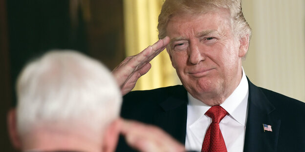 US-Präsident Donald Trump salutiert vor einem weißhaarigen Mann US-Präsident Donald Trump salutiert vor einem weißhaarigen Mann