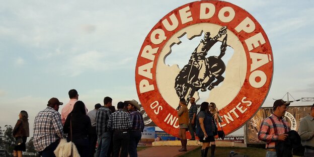 Menschen stehen um ein großes Rodeo-Log Menschen stehen um ein großes Rodeo-Log