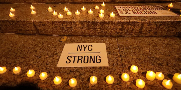 Teelichter stehen auf Treppenstufen, daneben Schilder mit der Aufschrift "NYC strong" und "Standing with Muslims against islamophobia and racism" Teelichter stehen auf Treppenstufen, daneben Schilder mit der Aufschrift "NYC strong" und "Standing with Muslims against islamophobia and racism"