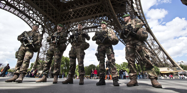 Fünf schwer bewaffnete Soldaten stehen unter dem Eiffelturm Fünf schwer bewaffnete Soldaten stehen unter dem Eiffelturm