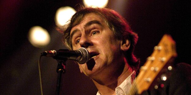 Ein Mann spielt Gitarre und singt in ein Mikrofon Ein Mann spielt Gitarre und singt in ein Mikrofon