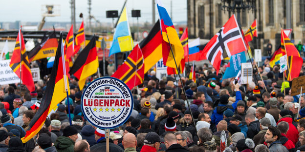 Pegida-Demonstrant*innen mit Flaggen und Schildern Pegida-Demonstrant*innen mit Flaggen und Schildern