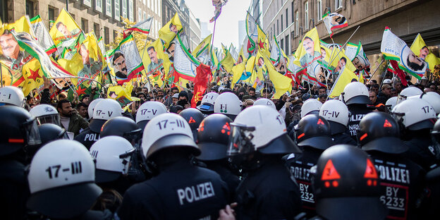 In einer Straße: im Vordergrund eine Polizeikette, dahinter Demonstranten mit gelben Fahnen In einer Straße: im Vordergrund eine Polizeikette, dahinter Demonstranten mit gelben Fahnen