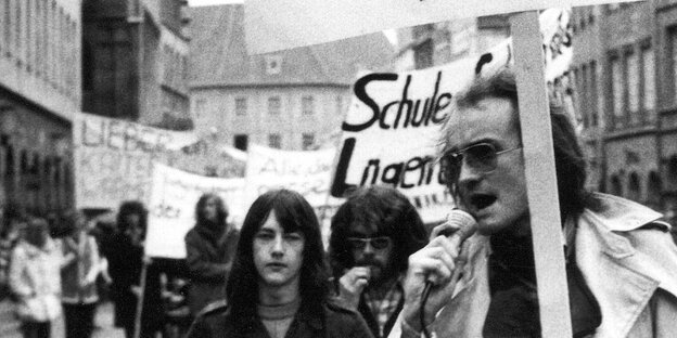 Ein Mann mit Sonnenbrille protestiert mit einem Schild in der Hand