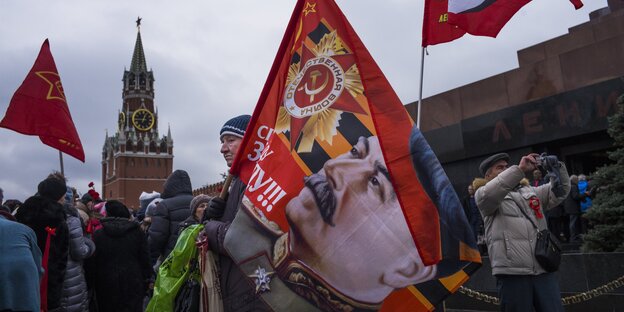 Menschen demonstrieren, einer trägt eine Fahne mit Stalins Konterfei Menschen demonstrieren, einer trägt eine Fahne mit Stalins Konterfei