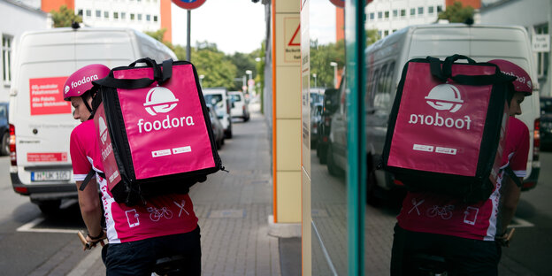 Ein Fahrradkurier mit pinkfarbenen Würfel auf dem Rücken steigt auf sein Fahrrad Ein Fahrradkurier mit pinkfarbenen Würfel auf dem Rücken steigt auf sein Fahrrad
