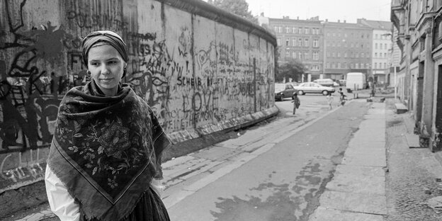 Eine Frau steht vor einem Stück der Berliner Mauer Eine Frau steht vor einem Stück der Berliner Mauer
