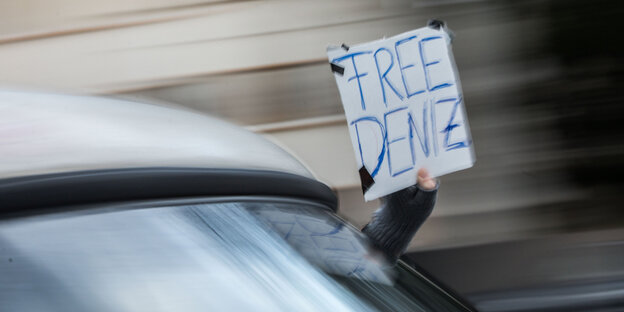 Eine Person hält aus einem fahrenden Auto ein Schild. Darauf steht „Free Deniz“ Eine Person hält aus einem fahrenden Auto ein Schild. Darauf steht „Free Deniz“