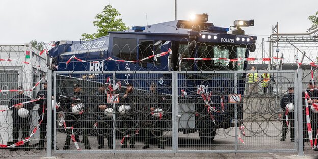 ein Wasdserwerfer hinter einem Zaun