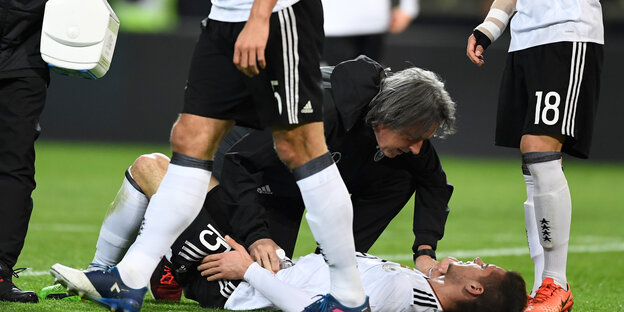 Hans-Wilhelm Müller-Wohlfahrt betreut einen Fußballspieler, der am Boden liegt Hans-Wilhelm Müller-Wohlfahrt betreut einen Fußballspieler, der am Boden liegt