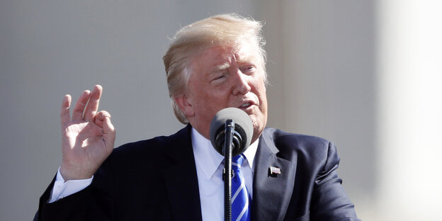 Donald Trump kneift das Gesicht, sowie Daumen und Zeigefinger seiner rechten Hand zusammen und spricht in ein Mikrofon Donald Trump kneift das Gesicht, sowie Daumen und Zeigefinger seiner rechten Hand zusammen und spricht in ein Mikrofon