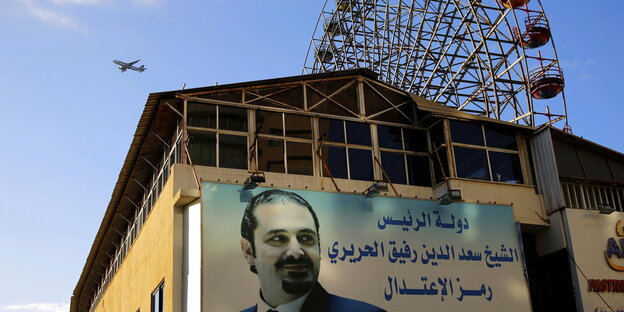 Ein Plakat mit Libamons Ex-Regierungschef Hariri an einer Hauswand, dahinter ein Riesenrad Ein Plakat mit Libamons Ex-Regierungschef Hariri an einer Hauswand, dahinter ein Riesenrad