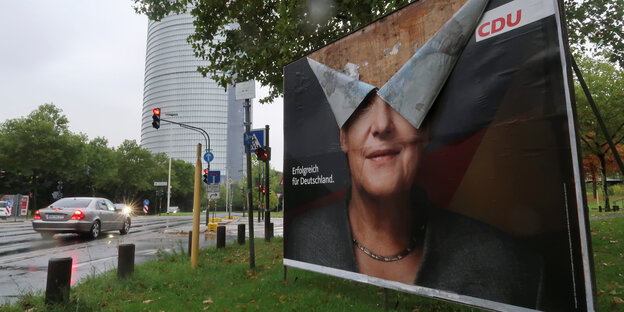 ein Wahlplakat mit Merkel-Kopf - stark beschädigt ein Wahlplakat mit Merkel-Kopf - stark beschädigt