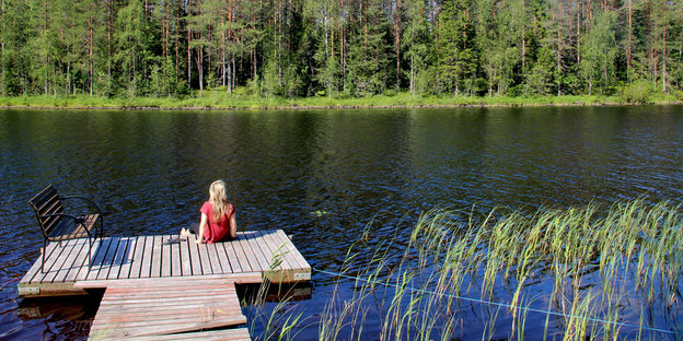 Eine Frau sitzt an einem See Eine Frau sitzt an einem See
