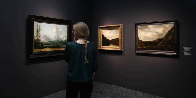 Eine Frau betrachtet Gemälde des Goldenen Zeitalters in einer Kunstausstellung Eine Frau betrachtet Gemälde des Goldenen Zeitalters in einer Kunstausstellung