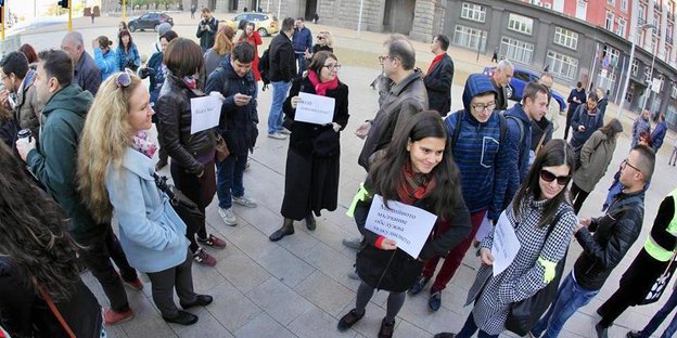 Eine Gruppe von Menschen steht zusammen auf einem Platz und hält Schilder in den Händen