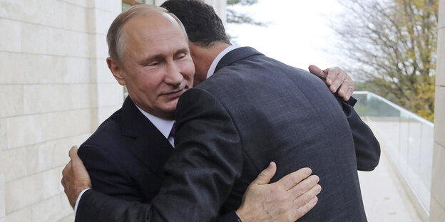 Assad, nur von hinten zu sehen, umarmt Putin demütig Assad, nur von hinten zu sehen, umarmt Putin demütig