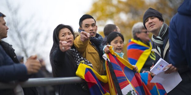 Ein Mann und eine Frau halten Tibet-Fahnen in den Händen und zeigen auf etwas, andere stehen um sie herum Ein Mann und eine Frau halten Tibet-Fahnen in den Händen und zeigen auf etwas, andere stehen um sie herum