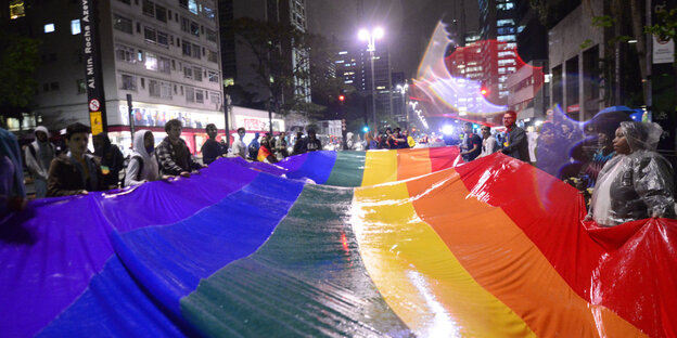 Viele Menschen halten eine extrem große Regenbogenfahne Viele Menschen halten eine extrem große Regenbogenfahne