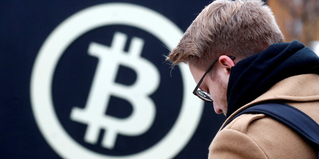 Ein Mann vor dem Bitcoin-Symbol Ein Mann vor dem Bitcoin-Symbol