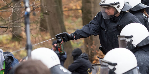 Behelmte Polizeibeamte sprühen Pfefferspray auf einen Aktivisten Behelmte Polizeibeamte sprühen Pfefferspray auf einen Aktivisten
