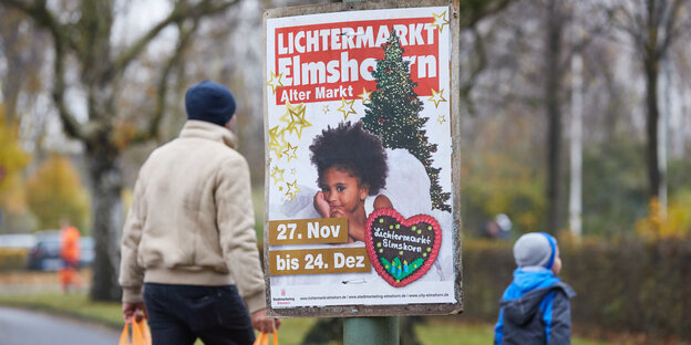 Werbeplakat für den Elmshorner Lichtermarkt an einem Pfahl, dahinter ein Mann mit Mütze und Plastiktüten Werbeplakat für den Elmshorner Lichtermarkt an einem Pfahl, dahinter ein Mann mit Mütze und Plastiktüten