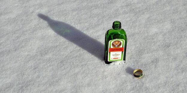 eine offene Jägermeisterflasche im Sand eine offene Jägermeisterflasche im Sand