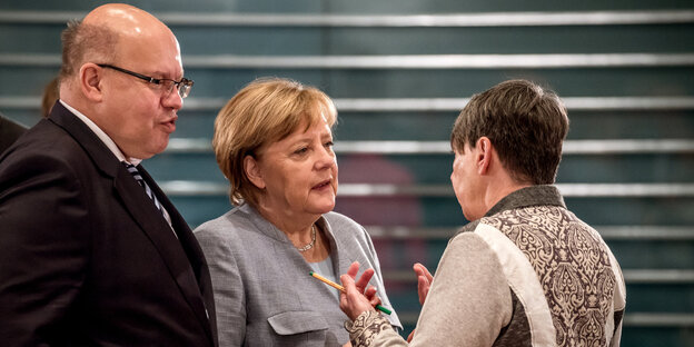 Zwei Frauen und ein Mann stehen zusamme und unterhalten sich Zwei Frauen und ein Mann stehen zusamme und unterhalten sich