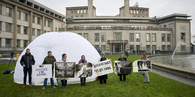 Menschen stehen vor einem Gebäude. Sie halten Plakate. Menschen stehen vor einem Gebäude. Sie halten Plakate.