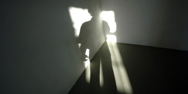 Schatten einer Person fällt durch das Fenster in ein leeres Zimmer Schatten einer Person fällt durch das Fenster in ein leeres Zimmer
