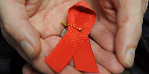 Hände halten eine Aids-Schleife Hände halten eine Aids-Schleife