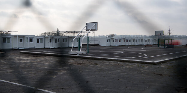 Contrainer stehen neben einem Basketballplatz