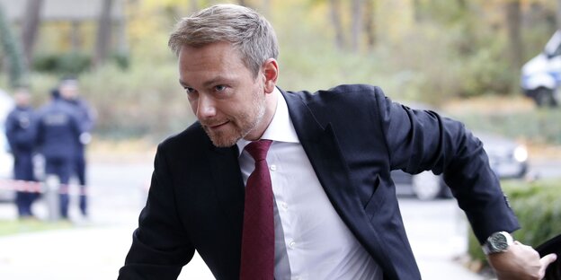 Ein Mann mit kurzen blonden Haaren und in Anzügen eilt durch das Bild, es ist Christian Lindner Ein Mann mit kurzen blonden Haaren und in Anzügen eilt durch das Bild, es ist Christian Lindner