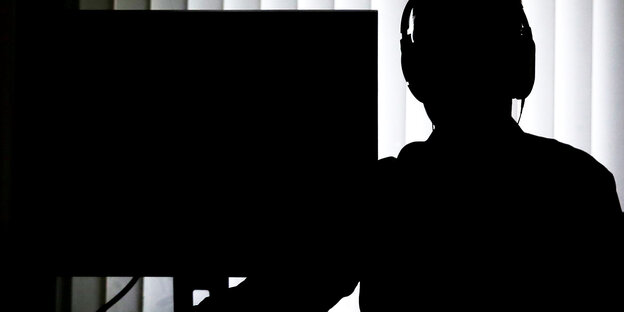 Ein Beamter sitzt für eine Telefonüberwachung mit Kopfhörern vor einem Computer Ein Beamter sitzt für eine Telefonüberwachung mit Kopfhörern vor einem Computer