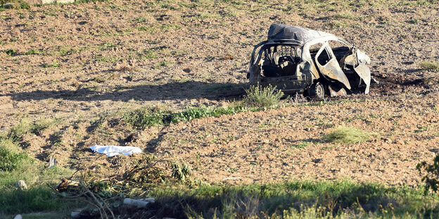 Ein ausgebranntes Autowrack auf einem Feld