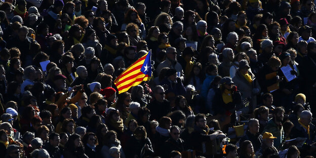 In einer Ansammlung von Menschen wird die Estelada-Flagge hochgehalten In einer Ansammlung von Menschen wird die Estelada-Flagge hochgehalten