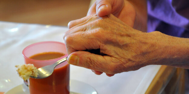 Junge Hand hilft alter Hand, eine Gabel zu halten Junge Hand hilft alter Hand, eine Gabel zu halten
