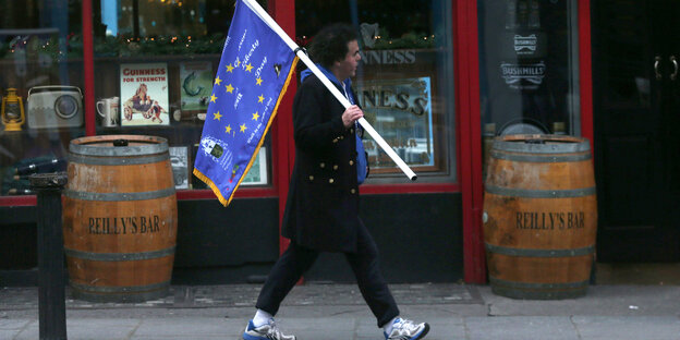 Ein Mann läuft durch Dublin mit einer Flagge in der Hand, die der der EU ähnelt Ein Mann läuft durch Dublin mit einer Flagge in der Hand, die der der EU ähnelt