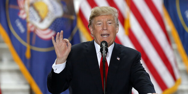 Trump spricht, im Hintergrund eine US-Fahne Trump spricht, im Hintergrund eine US-Fahne