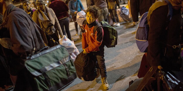 Ein junger Migrant trägt eine Tasche von Bord der Passagierfähre Blue Star 2 in der Hafenstadt Piräus, in der Nähe von Athen, Griechenland Ein junger Migrant trägt eine Tasche von Bord der Passagierfähre Blue Star 2 in der Hafenstadt Piräus, in der Nähe von Athen, Griechenland