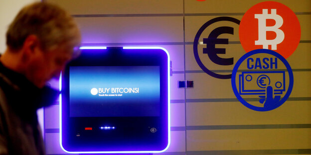 Ein Mann geht an einem Bitcoin-Automaten vorbei. Ein Mann geht an einem Bitcoin-Automaten vorbei.