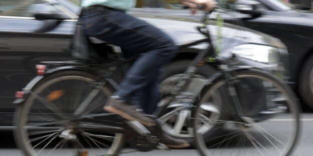 Nahaufnahme Radfahrer und Auto nebeneinander in Bewegung Nahaufnahme Radfahrer und Auto nebeneinander in Bewegung