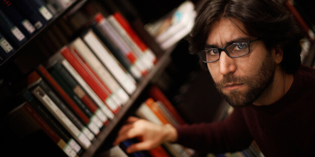 Ein Mann steht vor einem Bücherregal Ein Mann steht vor einem Bücherregal