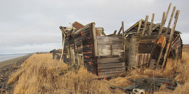 Die Ruine eines Holzhauses steht auf einem Hügel vor dem Nordpazifik