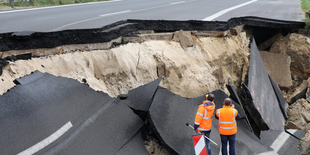 Zwei Menschen in Warnwesten stehen an der eingestürzten Autobahn Zwei Menschen in Warnwesten stehen an der eingestürzten Autobahn